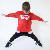 Young boy, wearing red shirt with long sleeves, with ski goggles print by KMLeon.