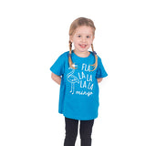 Blonde girl with pigtails wearing aqua shirt with 'Fla la la la la mingo' print by KMLeon, with hands behind her back.