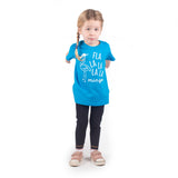 Blonde girl with pigtails wearing aqua shirt with 'Fla la la la la mingo' print by KMLeon, ready to jump.