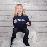 Smiling blonde girl wearing navy shirt with 'I'm having a meltdown' print by KMLeon.