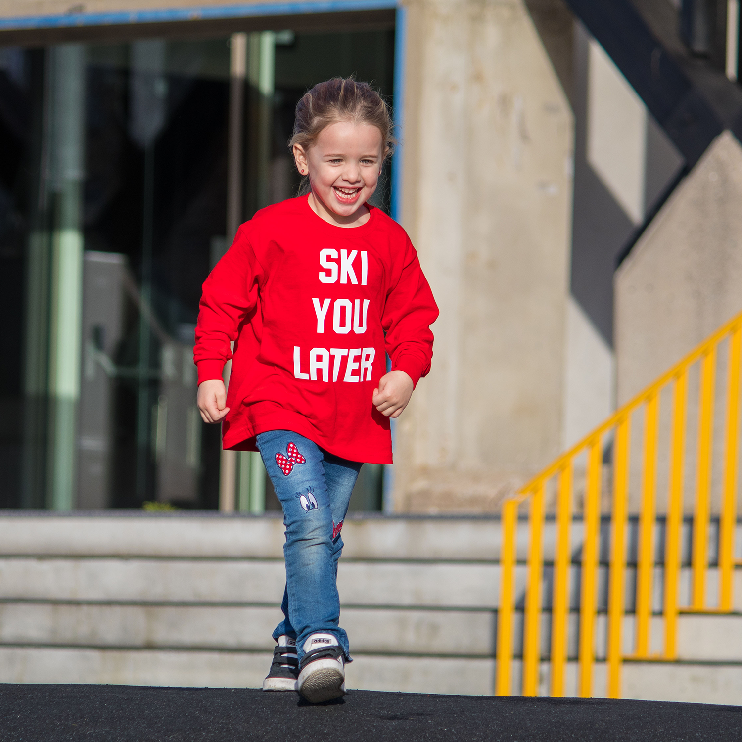 Blonde girl with red shirt with 'Ski you later' print by KMLeon walking.