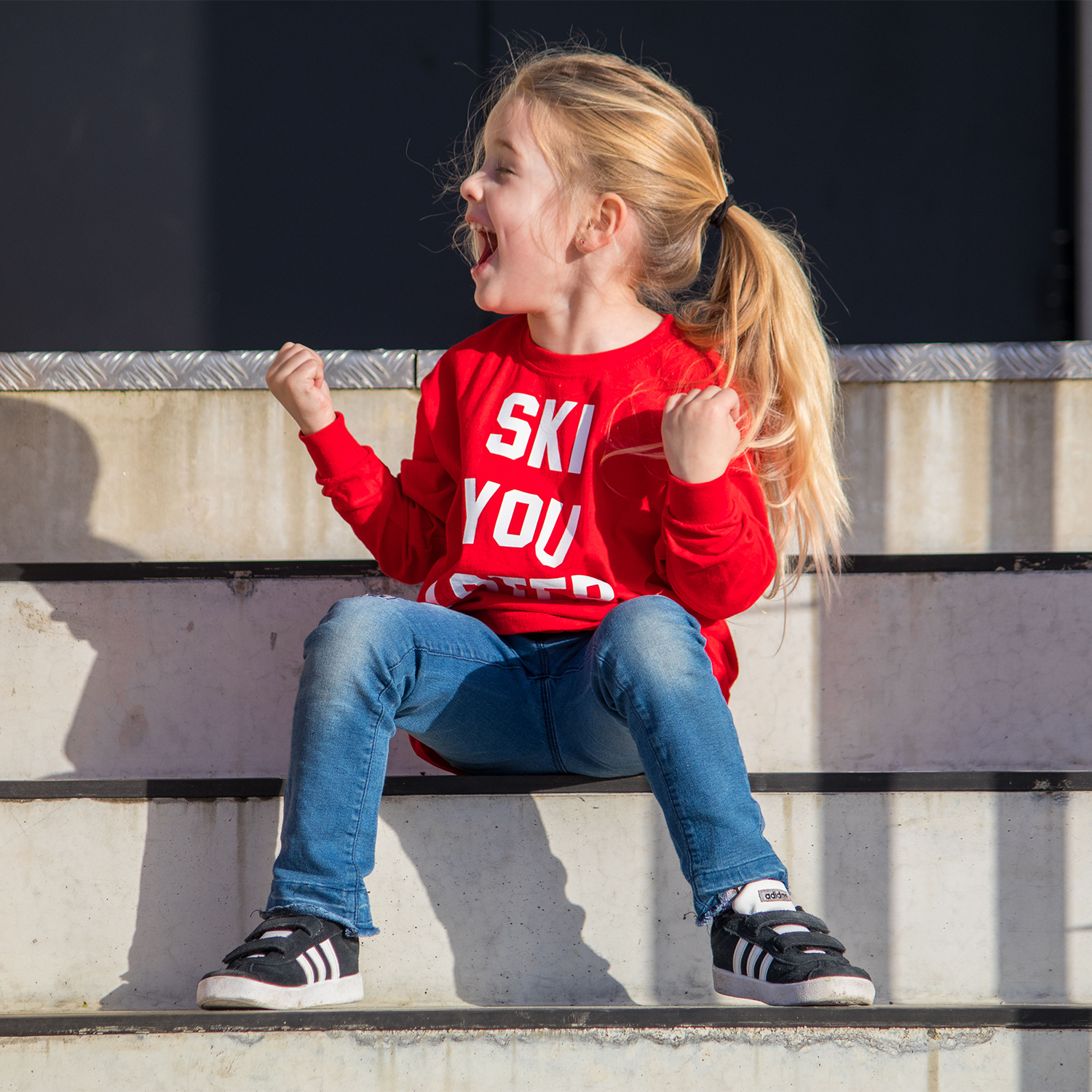 Happy blonde girl with red shirt with 'Ski you later' print by KMLeon screaming of joy.