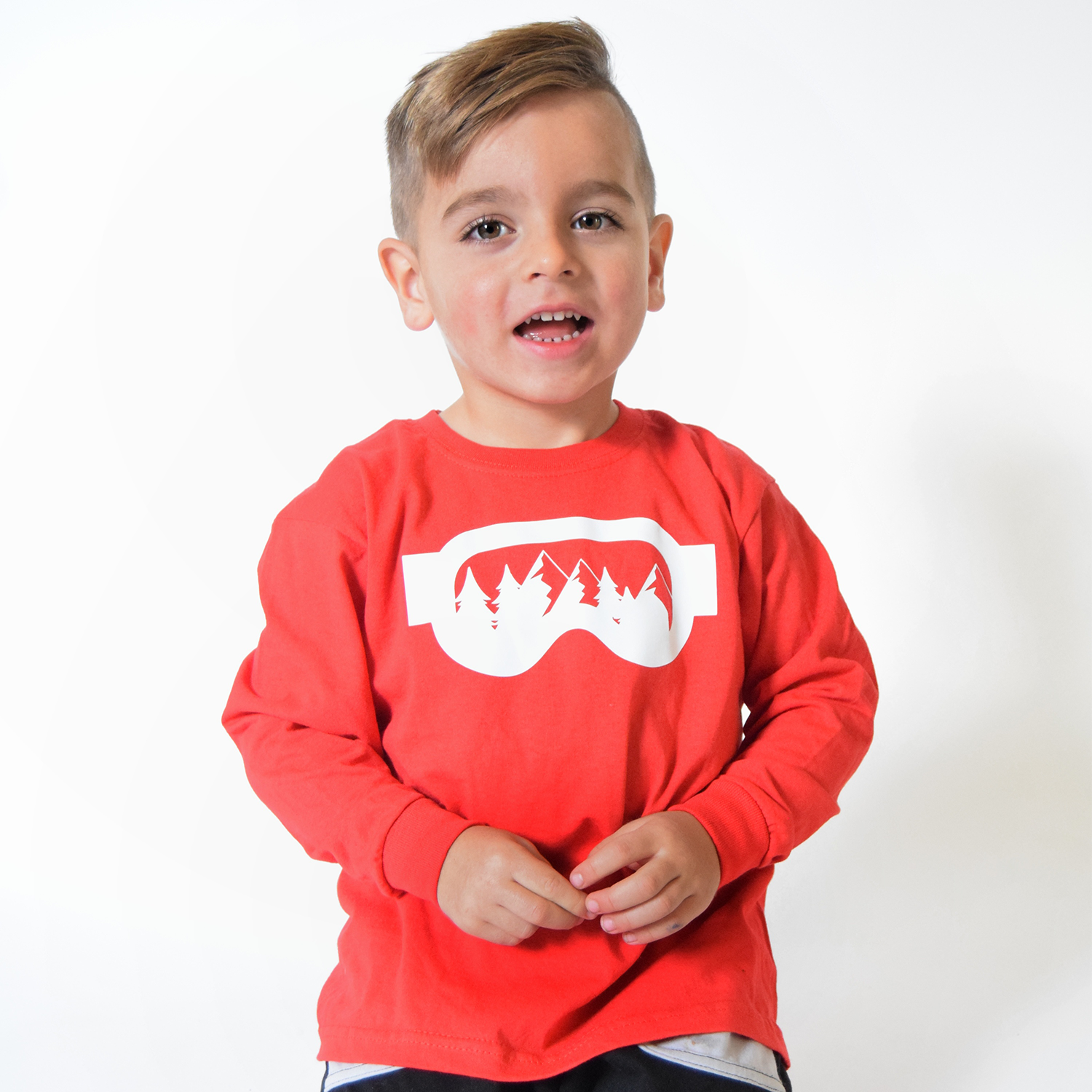 Young boy laughing, wearing red shirt with long sleeves, with ski goggles print by KMLeon.