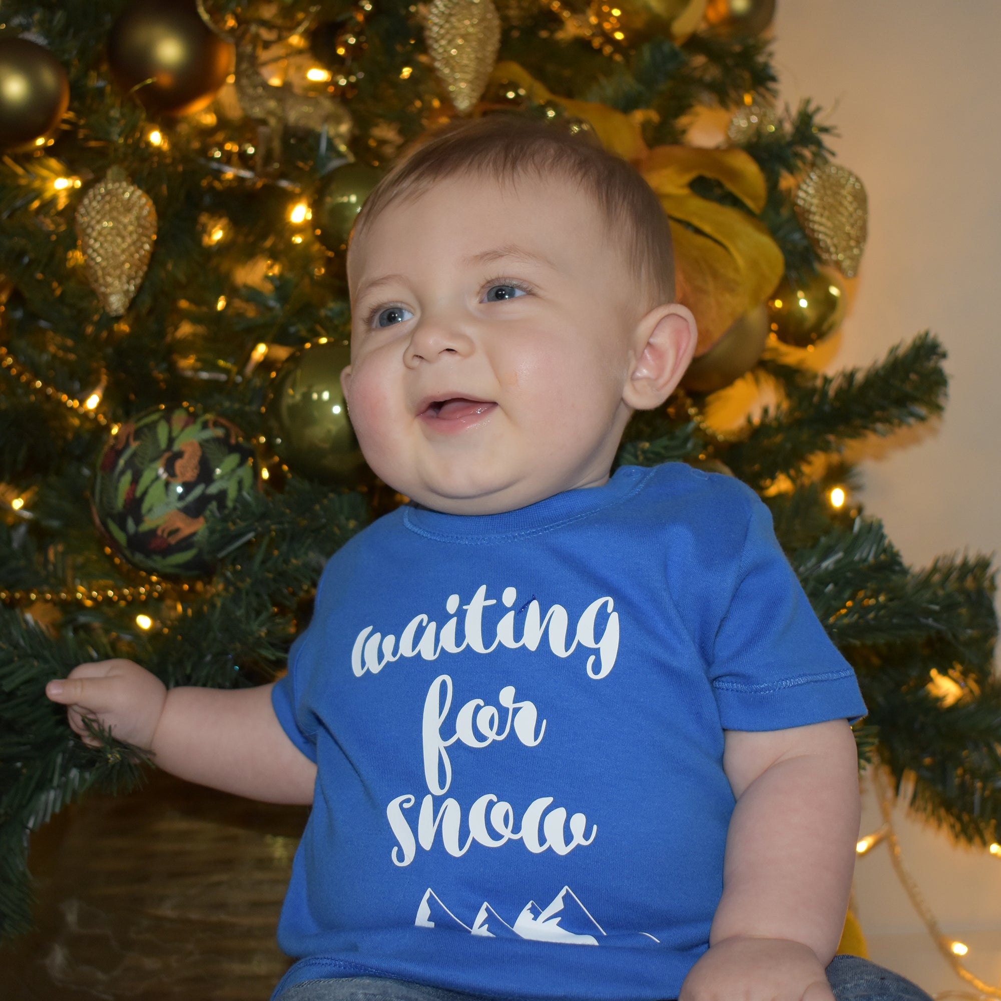 Little boy in front of christmas tree, wearing blue shirt with 'Waiting for snow' print by KMLeon.