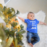 Little boy laying on white carpet, wearing blue shirt with 'Waiting for snow' print by KMLeon.