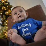 Little boy in front of christmas tree, wearing blue shirt with 'Waiting for snow' print by KMLeon.