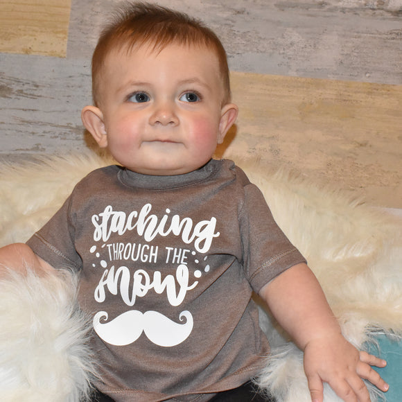 Toddler boy wearing mocha shirt, with 'Staching through the snow' print by KMLeon.