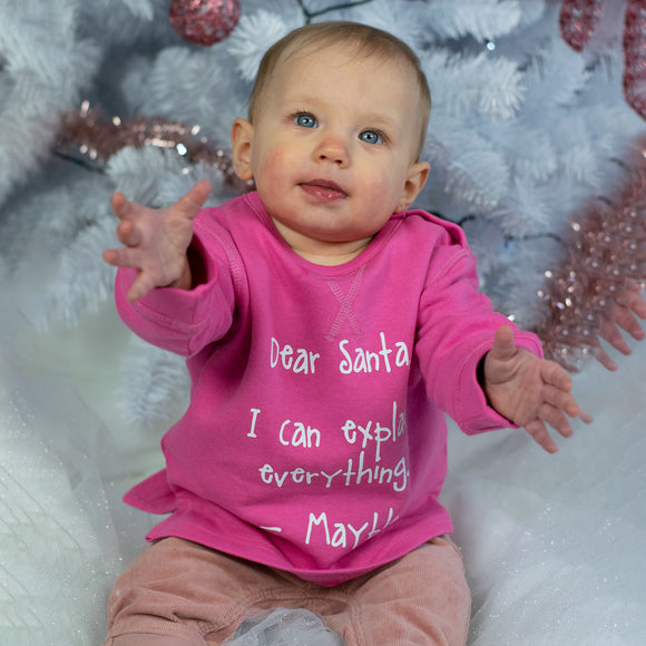 Baby girl with blue eyes and pink sweater with 'Santa, I can explain everything' sweater by KMLeon.