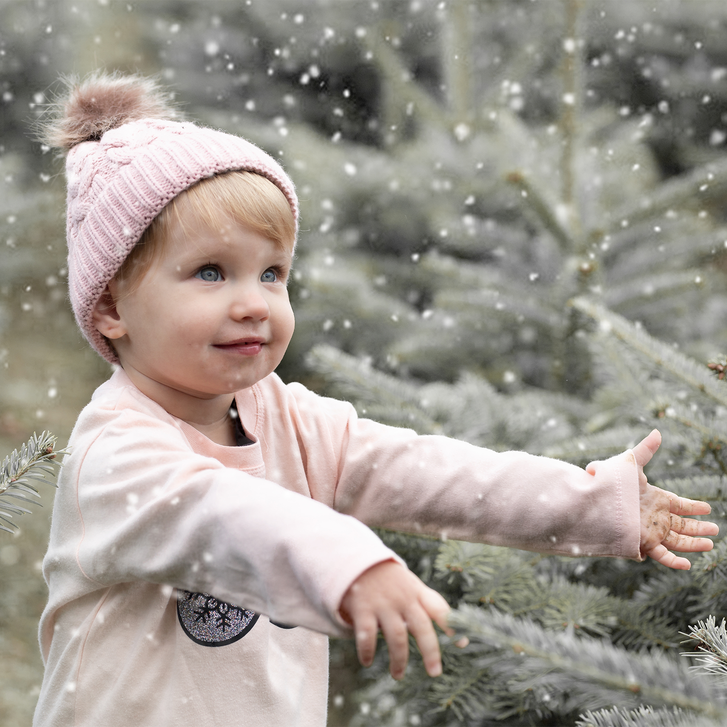 Blonde girl with pink beanie wearing pink shirt with long sleeves with glitter snow flake glasses print by KMLeon, feeling the snow.