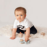 Little boy wearing white shirt with ski goggles print by KMLeon playing with toys.