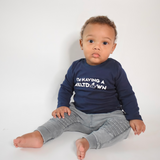 Black boy sitting wearing navy shirt with longs sleeves with 'I'm having a meltdown' print by KMLeon.