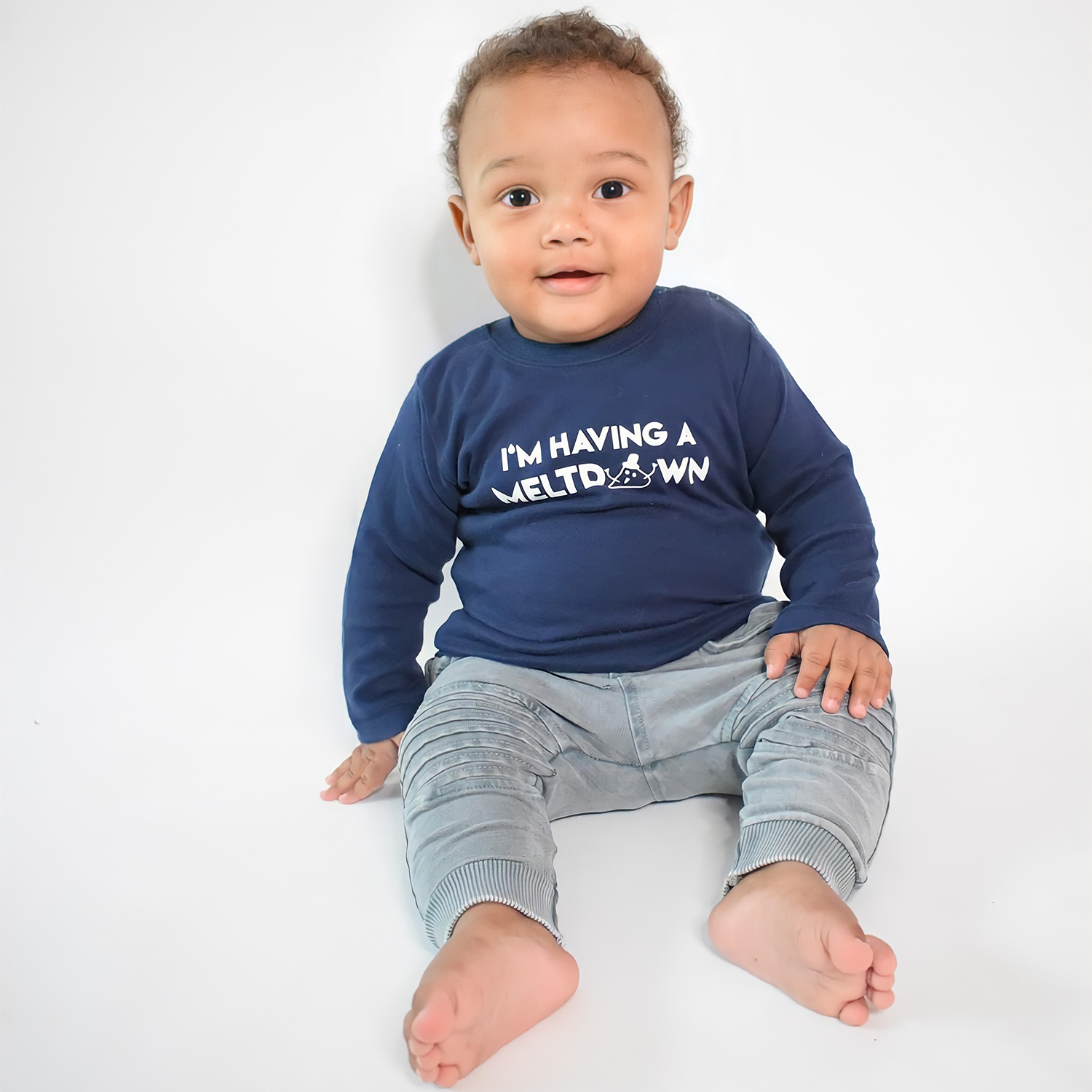 Smiling black boy sitting wearing navy shirt with longs sleeves with 'I'm having a meltdown' print by KMLeon.